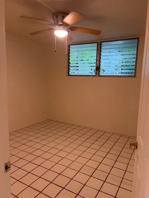 A room with a ceiling fan and a window with blinds.